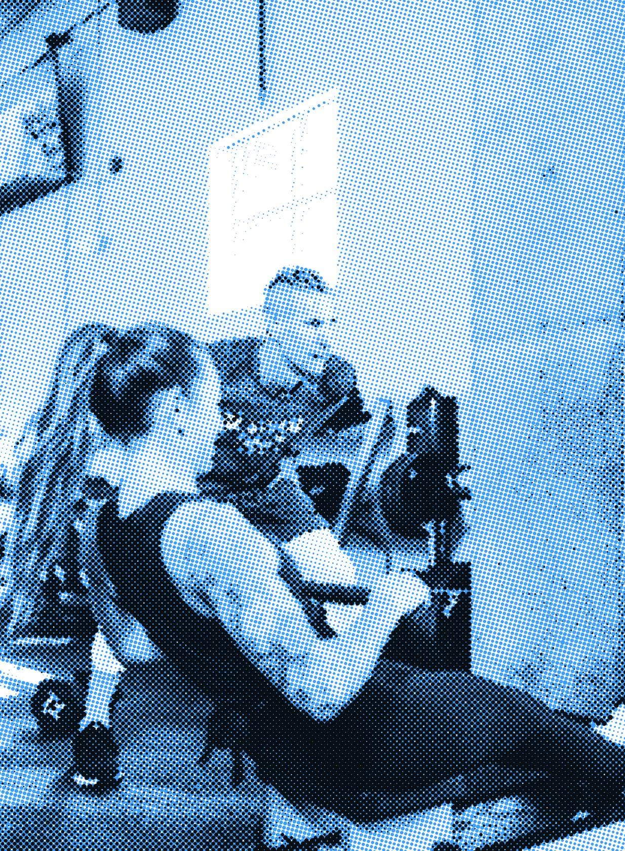 A coach guiding an athlete through a lift in the gym.